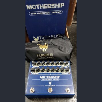 Modrý kytarový pedál s bílými popisky a nápisy MOTHERSHIP, TUBE OVERDRIVE - PREAMP, Tsakalis AudioWorks a CH 1/2. Zařízení má dvě řady ovládacích kno…