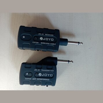 Dva černé plastové moduly bezdrátového systému s jack konektory. Horní modul nese nápisy JW-01 RECEIVER, JOYO a CATCH WIRELESS CABLE. Dolní modul obs…