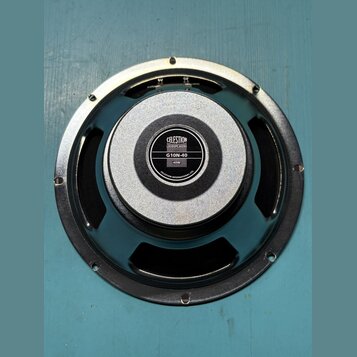 Fotografie znázorňuje zadní stranu černého reproduktoru. Uprostřed je umístěn štítek s nápisy CELESTION, GUITAR SPEAKERS, G10N-40 a 40W. Okraj štítku…