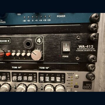 Detailní pohled na rackové studio zařízení. Uprostřed je černý panel s nápisem WA-412 a textem TRANSFORMER BALANCED 4 CHANNEL DISCRETE MIC PRE, vybav…