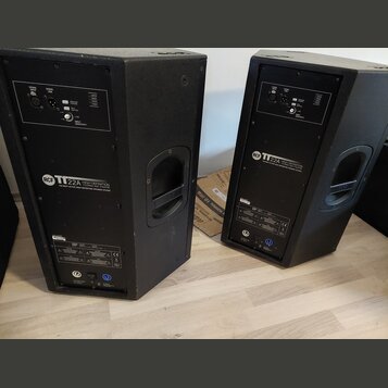 Dva černé aktivní reproduktory v plastových bednách s úchopovými madly. Na zadním panelu obou kusů je bílý nápis RCF TT 22A HIGH DEFINITION TOUR LINE…