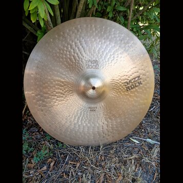 Kovový činel s kladivkovaným povrchem a zlatavou barvou. Na povrchu jsou vyraženy nápisy „paiste 2002“, „JAZZ ROCK“ a „HEAVY RIDE“. Povrch vykazuje d…