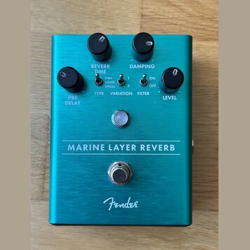 Tyrkysový efekt pedál s kovovým povrchem. Na přední straně jsou čtyři černé ovládací knoflíky s popisky PRE DELAY, REVERB TIME, DAMPING a LEVEL, tři…