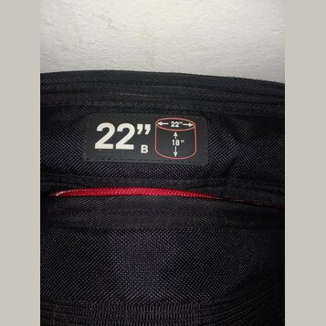 Detail černé texturované látky s přišitou černou štítkem. Na štítku je bílý nápis 22" B a schéma obdélníku s rozměry 22" a 18". Pod štítkem je vidite…