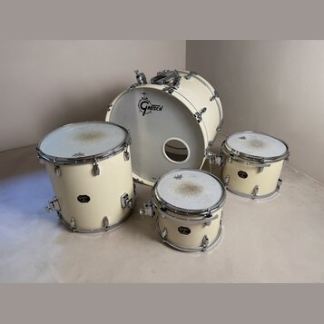 Sada bicích bubnů v krémové barvě s chromovaným hardwarem. Na přední kožeh basového bubnu je černé logo GRETSCH. Ostatní bubny mají na korpusu malé č…