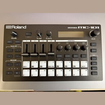 Černá groovebox s bílými nápisy a logem Roland. V pravém horním rohu je modelové označení GROOVEBOX MC-101. Zařízení obsahuje displej, několik otočný…