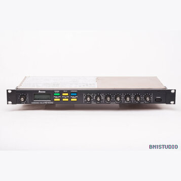 Černý rackový efektový procesor s nápisem HARMONICS/DELAY HD 1000. Na předním panelu je logo Ibanez, digitální displej a několik barevných tlačítek s…