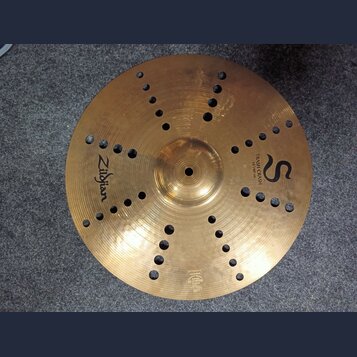 Zlatý kovový činel s otvory v povrchu. Na povrchu jsou nápisy Zildjian, TRASH CRASH a 16"/40 cm spolu s logem ve tvaru písmene S. V dolní části je dr…