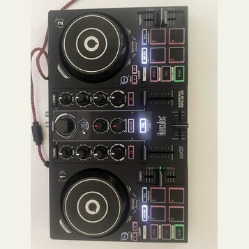 Černý DJ kontrolér s dvěma jog-koly a centrální sekcí s knoflíky a posuvníky. Na přístroji jsou viditelné nápisy Hercules, DJCONTROL IMPULSE 200 a DJ…