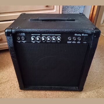 Černý basový kombozesilovač s texturovaným povrchem a černou ochrannou síťkou. Na horním ovládacím panelu jsou nápisy HB-40B BASS AMPLIFIER a Harley…