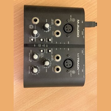 Černý zvukový interface M-AUDIO M-TRACK PLUS. Zařízení má dva identické vstupní kanály s popisky MIC INPUT (1 a 2), GUITAR/LINE INPUT, INSERT a ovlad…