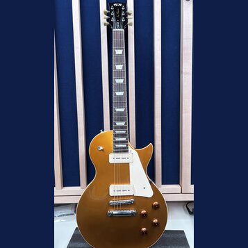Zlatá elektrická kytara s tmelejším hmatníkem a bílým pickguardem. Na hlavě je bílé logo FGN a nápis Les Custom. Nástroj má dva humbuckery s bílými k…