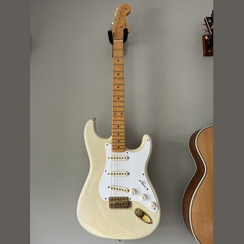 Bílá elektrická kytara s jasným dřevěným hmatníkem a bílým pickguardem. Na hlavě krku je viditelné logo Fender. Nástroj má tři snímače s bílými krytk…