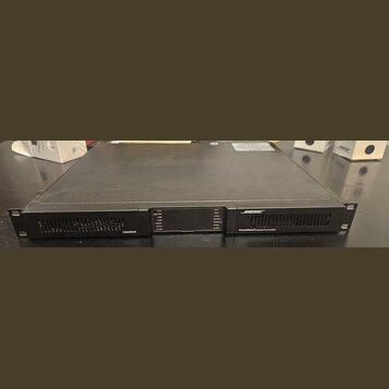 Černý rackový zesilovač s kovovým povrchem. Na předním panelu je vlevo nápis PSX1204D, uprostřed kontrolní panel s LED indikátory a vpravo logo BOSE…
