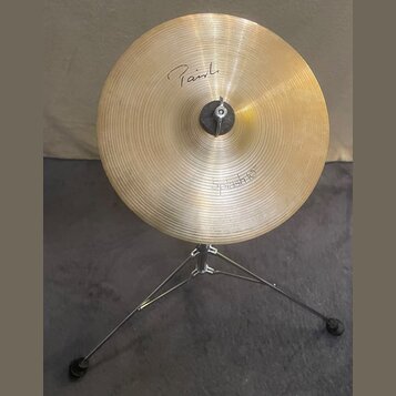 Zlatý kovový činel typu splash na černém stativu. Na povrchu je nápis "Paiste" a v dolní části označení "Splash 10"". Povrch činelu vykazuje jemné ko…