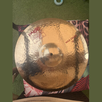 Kovový činel s kladeným povrchem v zlatavé barvě. Na povrchu je nápis „paiste 2002“ v obdélníkovém rámečku s doplňkem „TRADE MARK MADE IN SWITZERLAND…