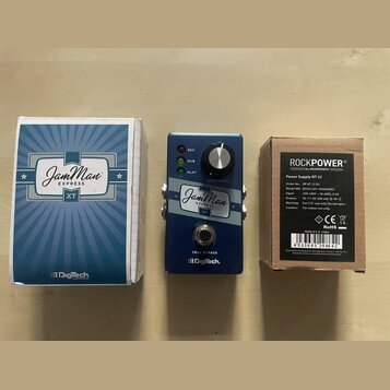 Na fotografii je modrý kytarový looper JamMan EXPRESS XT značky Digitech, jeho originální krabice a napájecí adaptér v kartonové krabičce. Na pedálu…