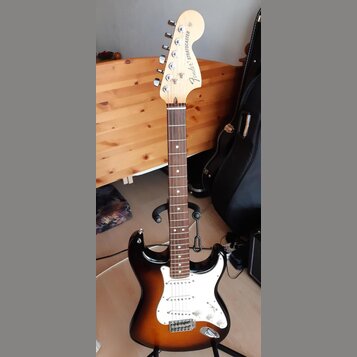 Elektrická kytara typu Stratocaster s korpusem v přechodové barvě od černé k hnědé a žluté. Má bílý pickguard, tři snímače a javorový krk s hmatníkem…