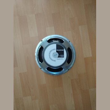 Fotografie znázorňuje reproduktor s kovovým rámem v stříbrné barvě. Na zadní části je bílo-černá nálepka s nápisy PROFESSIONALLOUDSPEAKER, CELESTION,…
