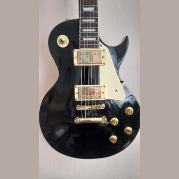 Černá elektrická kytara s typickým tvarem singlecut a krémovým pickguardem. Má dva humbuckery se zlatými kryty, zlatý kobylník a čtyři zlaté ovládací…