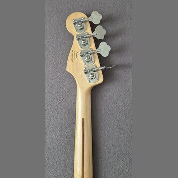 Zadní strana hlavy a krku světlé dřevěné basové kytary. Na hlavě jsou čtyři kovové ladičky a nápisy „Fender“, „Custom Offset“, „Made in USA“ a sériov…