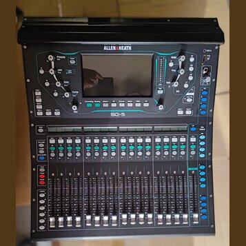 Černý digitální mixážní pult značky ALLEN&HEATH, model SQ-5. Zařízení má v horní části displej a ovládací prvky s modrým podsvícením, ve spodní části…