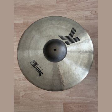 Kovový činel v matné stříbrno-zlaté barvě s viditelnou strukturou povrchu. Na povrchu je černý nápis SWEET CRASH a menší text 19" / 48 cm. V horní čá…