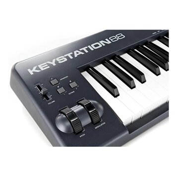 Detailní pohled na levou část černé MIDI klávesnice s bílými a černými klávesami. Na horní hraně je bílý nápis KEYSTATION88. Ovládací panel obsahuje…