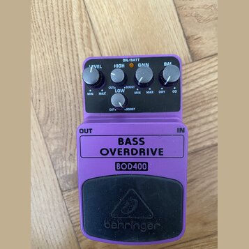 Fialový efekt pedál s nápisy BASS OVERDRIVE a BOD400. V horní části jsou čtyři ovládací knoflíky s popisky LEVEL, HIGH, GAIN a BAL. Pod nimi se nachá…