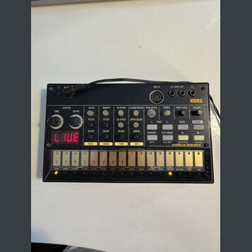 Černý drum machine s nápisy KORG a volta beats. Zařízení obsahuje několik otočných potenciometrů, tlačítek a červený digitální displej s viditelným t…