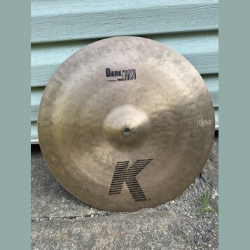Kruhový mosazný činel s viditelným kovánívým vzorem. Na povrchu jsou nápisy DARK CRASH a 17"/43 cm Thin. Ve spodní části je velké logo K, vpravo u ok…