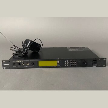 Černý rackový tónový generátor s nápisy YAMAHA a MU90 PRO TONE GENERATOR. Na předním panelu je umístěn LCD displej, několik ovládacích tlačítek, dva…