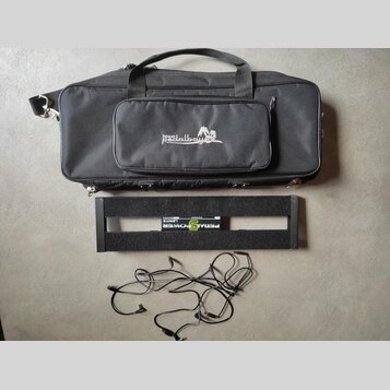 Černá transportní taška s nápisem Palmer pedalbay 4plus. Pod ní je černý kovový pedalboard s nápisem PEDALPOWER a LEWITZ. V dolní části jsou rozložen…