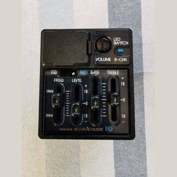 Černý plastový předzesilovač s ovládacími prvky. Na panelu jsou nápisy LED SWITCH, VOLUME, B-CHK a posuvníky s označením EQ, PASS, BASS, TREBLE, FREQ…