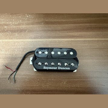 Černý humbucker s plastovým krytem a bílým rámečkem. Na boku je bílý nápis Seymour Duncan. Snímač má šest viditelných pólů, z nichž jedna řada je zak…