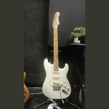 Bílá elektrická kytara typu Stratocaster s jasným dřevěným hmatníkem a hlavou. Na hlavě je viditelné logo Squier. Nástroj má tři snímače typu single-…