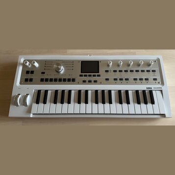 Bílá klávesová syntezátor s nápisem KORG microKORG synthesizer vocoder. Přístroj má v horní části ovládací panel s několika otočnými knoflíky, tlačít…