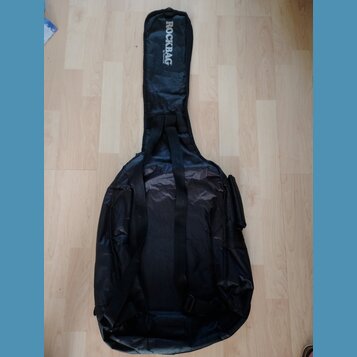 Černý textilní obal na hudební nástroj s ramenními popruhy a boční kapsou. Na horní části je bílý nápis ROCK BAG a pod ním menší text by HARLEY BENTO…