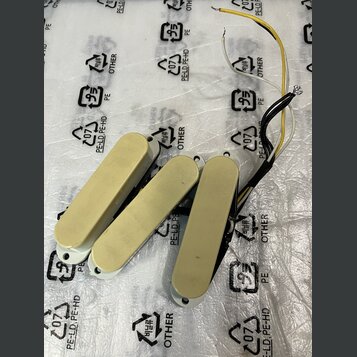 Tři elektrické snímače pro kytaru v krémové barvě. Snímače mají obdélníkový tvar se zaoblenými konci a jsou vybaveny připojovacími kabely v černé, žl…