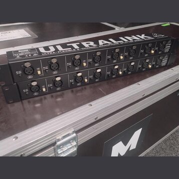 Dvě černé rackové jednotky s nápisy ULTRALINK a ULTRA-FLEXIBLE 6-CHANNEL MICROPHONE SPLITTER MODEL MS8000. Na předním panelu jsou vidět vstupy, přepí…