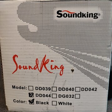 Fotografie znázorňuje část bílého kartónového obalu. V horní části je černý nápis Soundking® a uprostřed červený nápis SoundKing. Dole jsou uvedeny m…