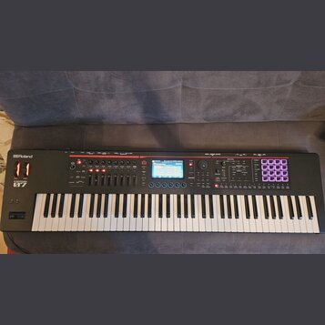 Černá klaviatura s bílými a černými klávesami. Na levé straně je nápis Roland a pod ním model FANTOM 07. Střední panel obsahuje displej, několik posu…