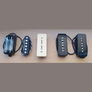 Fotografie zobrazuje pět elektrických snímačů kytary v různých provedeních. Zleva jsou dva černí humbuckery s nápisem Seymour Duncan, jeden krémový j…