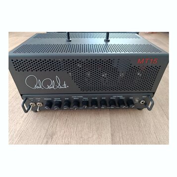 Černý kytarový zesilovač s perforovaným kovovým šasi. Na přední straně je bílý nápis Paul Reed Smith® a v pravém horním rohu červený nápis MT15. Před…