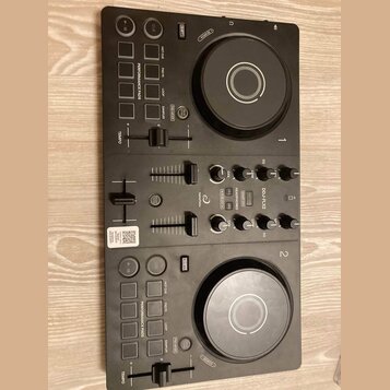 Černý DJ kontrolér s dvěma jog-koly, faderem a řadou ovládacích tlačítek a posuvníků. Na přístroji je vidět nápis DDJ-FLX2, logo AlphaTheta a označen…
