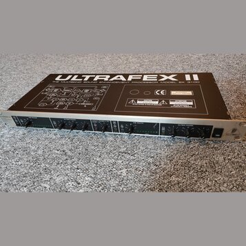 Černý rackový procesor s nápisem ULTRAFEX II a THE MULTIBAND SOUND ENHANCEMENT PROCESSOR MODEL EX 3100. Na horním krytu je schéma zapojení, značka CE…