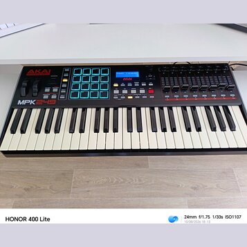 Černý MIDI kontrolér s klávesnicí. Na levé straně je nápis AKAI PROFESSIONAL a modelové označení MPK249. Přístroj obsahuje modrý podsvícený pad kontr…