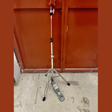 Stříbrný kovový stativ s černými plastovými prvky a trojnožkou. Na spodní části je připevněn šedý plastový pedalboard. Povrch stativu vykazuje známky…