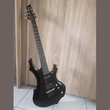 Černá elektrická kytara s ostrými hranami korpusu a hmatníkem z tmavého dřeva. Na hlavě je bílé logo Ltd. Nástroj má dva humbuckery, jeden ovládací k…