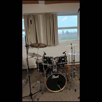 Černá bicí souprava značky Pearl s kovovým hardwarem. Sestává z basového bubnu s logem Pearl, dvou tomů, jednoho floor tomu a tří činelů. Nástroje js…